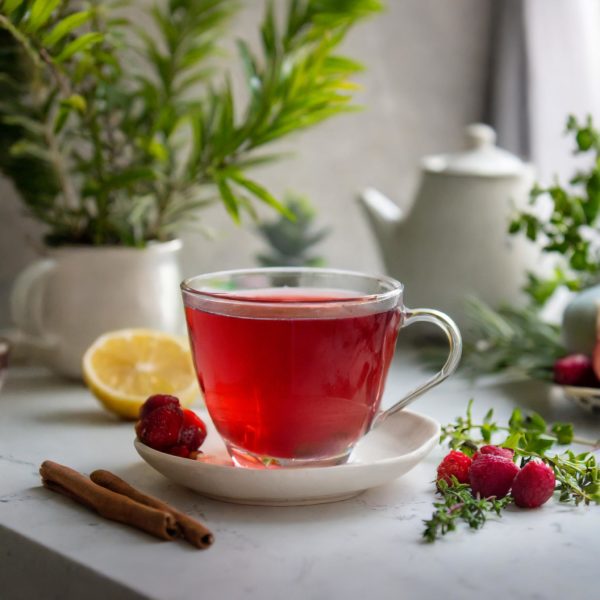Tasse de thé aux fruits rouges prête à être consommée avec des fruits rouges autours