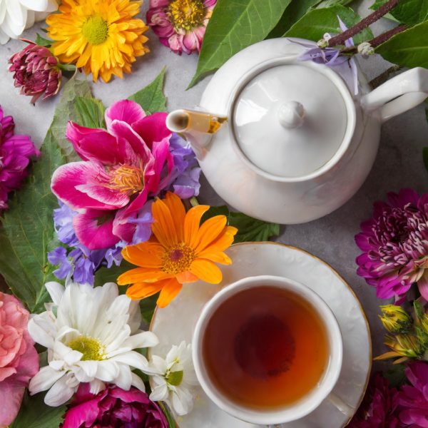 Théière de thé aux fleurs avec une tasse de thé avec des fleurs très colorées
